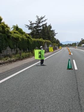 高速道路の規制の出入口付近にて減速旗を使い交通誘導する様子