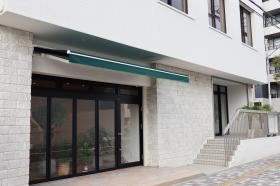 ビル外観（緑色のオーニングが白壁のアクセントになっています）